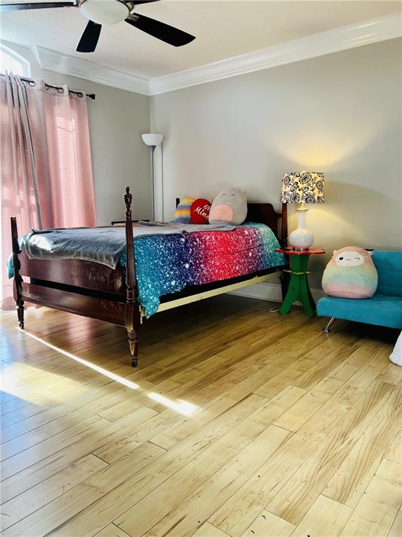 bedroom featuring ceiling fan, crown molding, and hardwood / wood-style floors