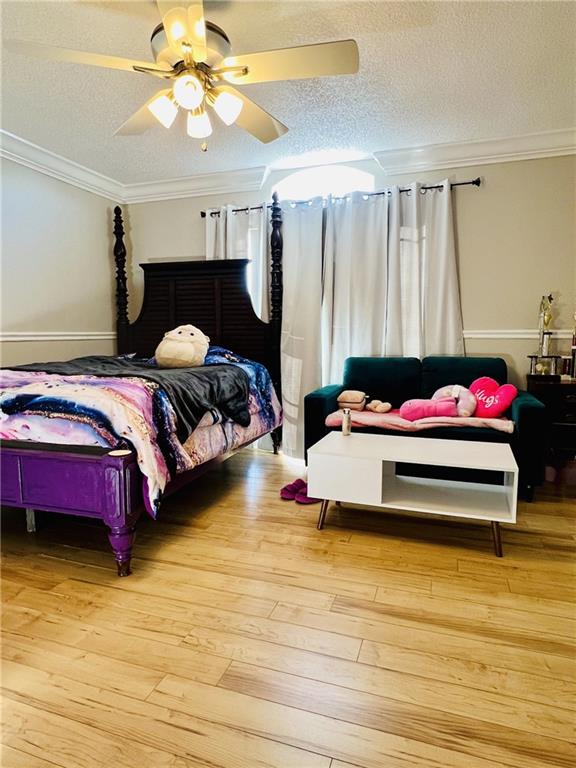 bedroom featuring ceiling fan, crown molding, a textured ceiling, and hardwood / wood-style floors