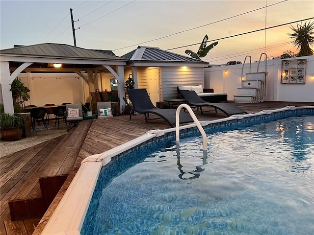 pool at dusk featuring a gazebo and a deck