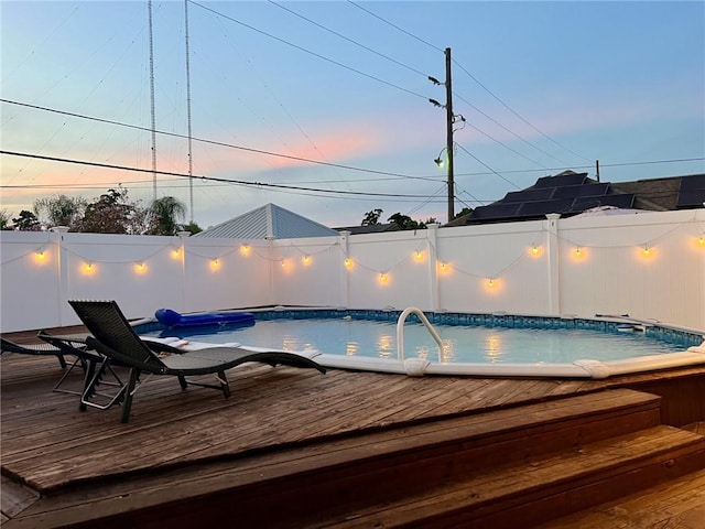 pool at dusk featuring a jacuzzi and a wooden deck