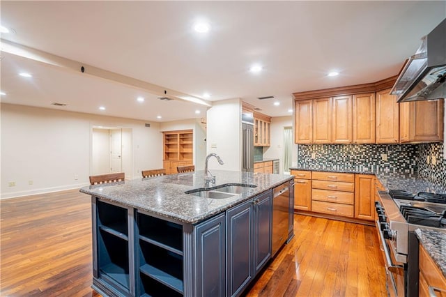 kitchen with an island with sink, stainless steel appliances, light hardwood / wood-style flooring, range hood, and sink