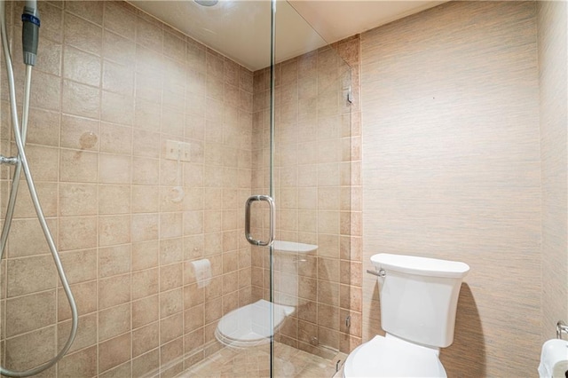 bathroom featuring a shower with shower door and toilet