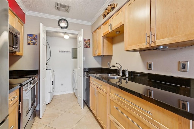 kitchen featuring appliances with stainless steel finishes, a textured ceiling, washer and clothes dryer, crown molding, and sink