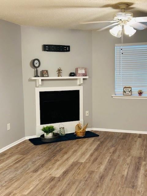 living room featuring a textured ceiling, wood-type flooring, and ceiling fan