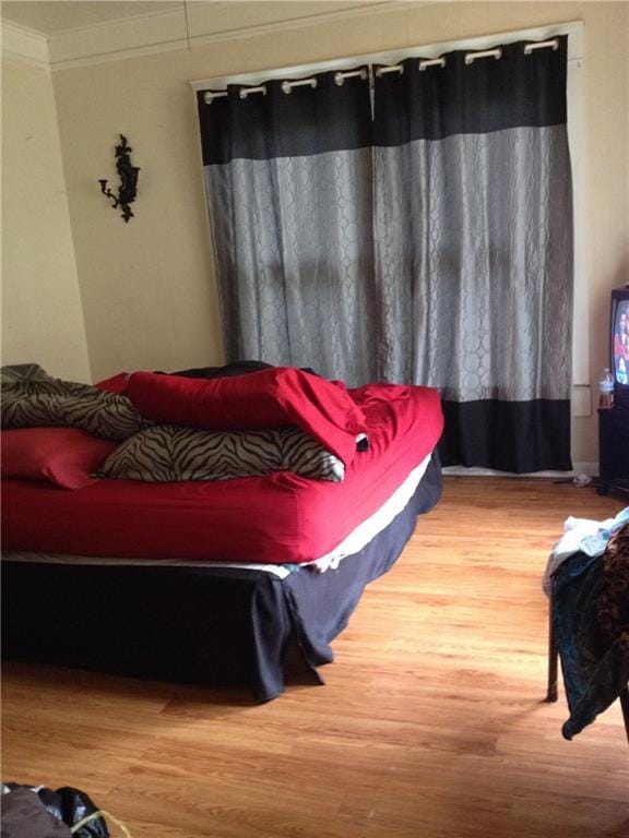 bedroom with wood-type flooring and ornamental molding