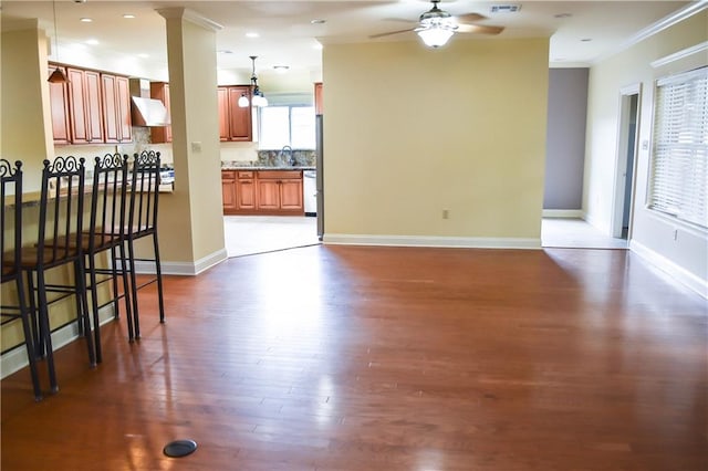 living room with dark hardwood / wood-style flooring, ceiling fan, decorative columns, ornamental molding, and sink