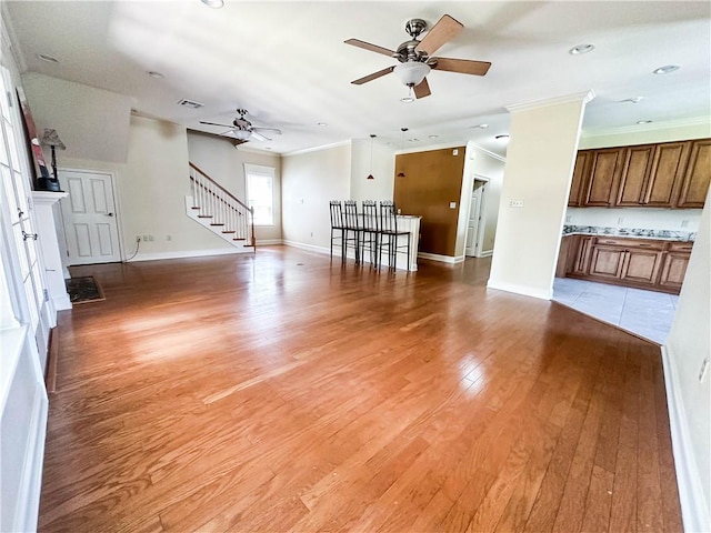 unfurnished living room with ceiling fan, ornamental molding, and light hardwood / wood-style floors