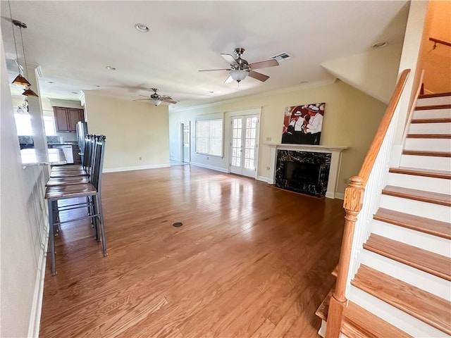 living room featuring ceiling fan, hardwood / wood-style flooring, crown molding, and a high end fireplace