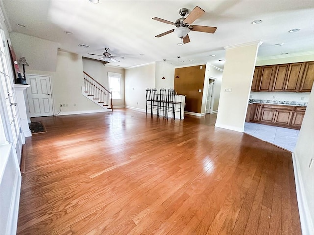 6613 Memphis St, New Orleans, LA 70124 - unfurnished living room featuring ceiling fan, light wood-style floors, crown molding, stairway, and baseboards