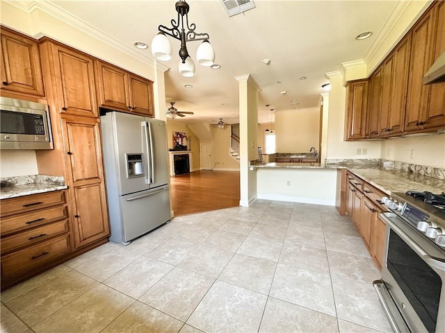 kitchen featuring ceiling fan with notable chandelier, stainless steel appliances, decorative light fixtures, crown molding, and light stone countertops