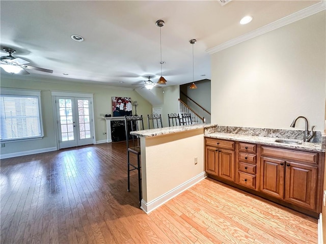 kitchen with a breakfast bar, kitchen peninsula, light hardwood / wood-style flooring, ceiling fan, and decorative light fixtures