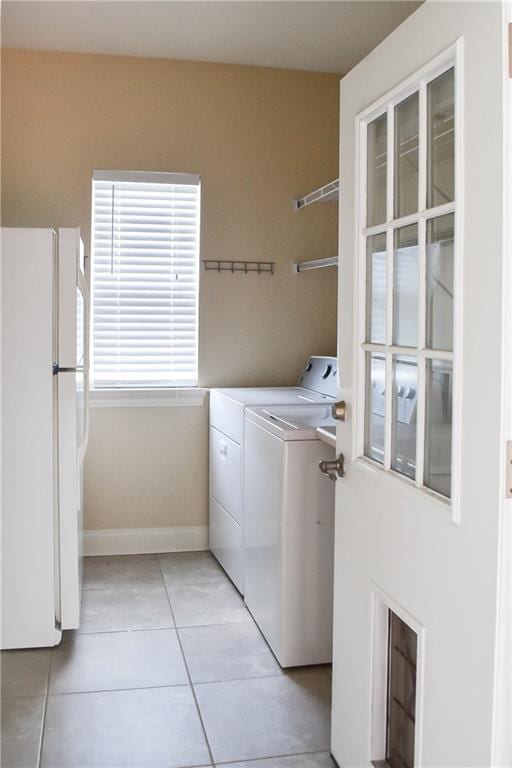 clothes washing area featuring washing machine and clothes dryer and light tile patterned floors