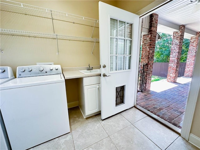 clothes washing area with light tile patterned floors, cabinets, and sink