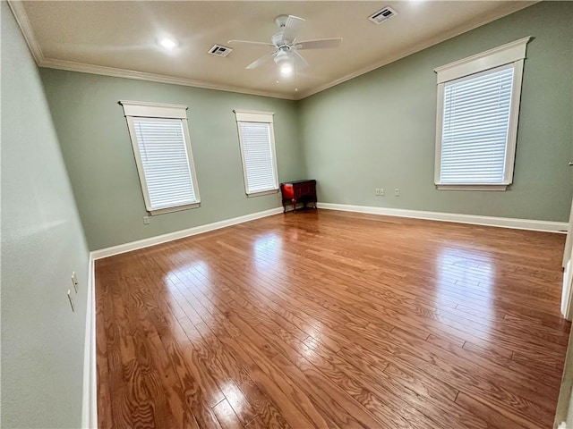 empty room featuring ceiling fan, light hardwood / wood-style flooring, ornamental molding, and a wealth of natural light