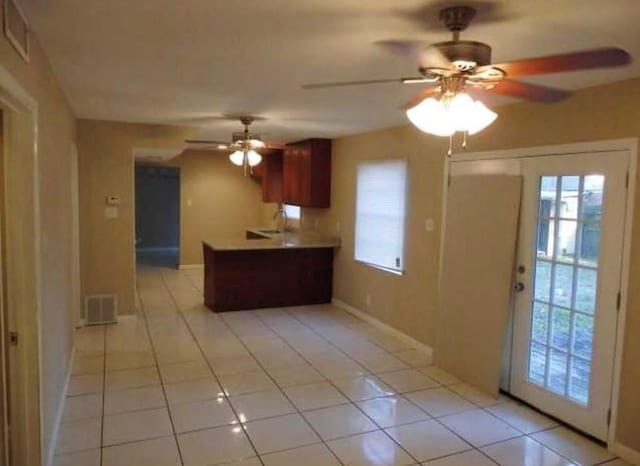 kitchen featuring kitchen peninsula, ceiling fan, light tile patterned floors, and sink