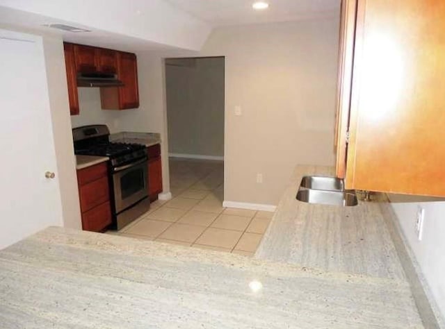 kitchen featuring light tile patterned floors and stainless steel gas range