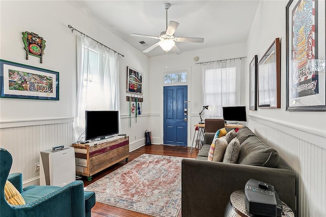 living area with visible vents, wainscoting, ceiling fan, and dark wood-style floors