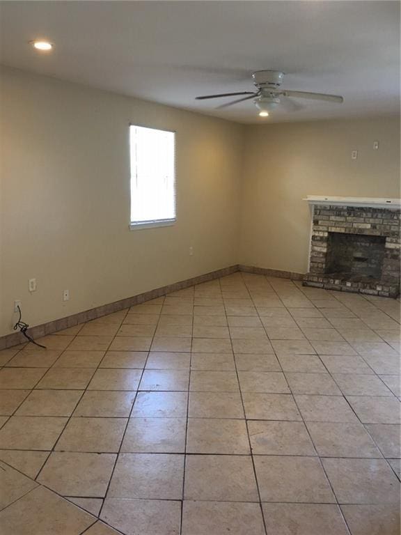 unfurnished living room with ceiling fan, light tile patterned flooring, and a brick fireplace