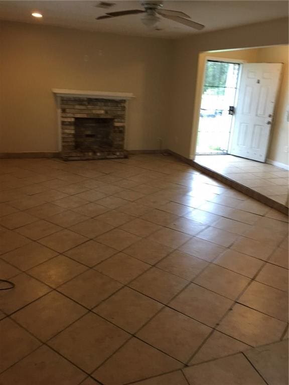 unfurnished living room with a fireplace, ceiling fan, and light tile patterned flooring