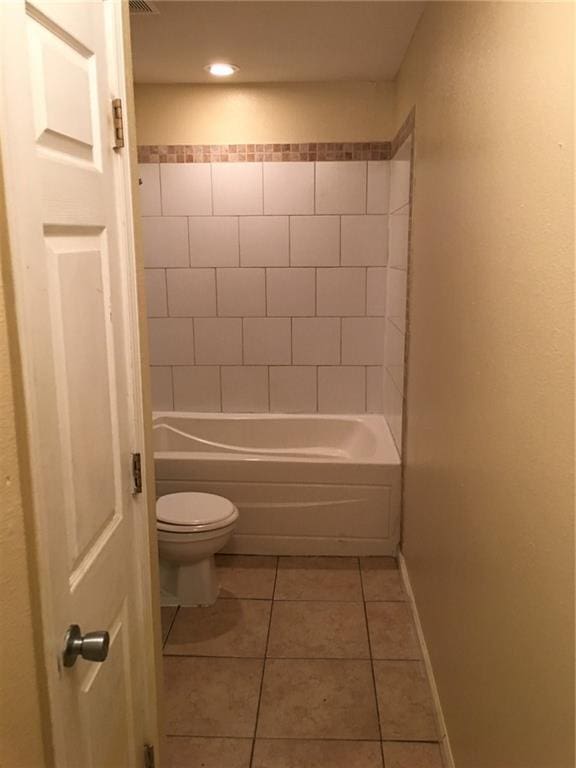 bathroom featuring tile patterned flooring, tiled shower / bath combo, and toilet