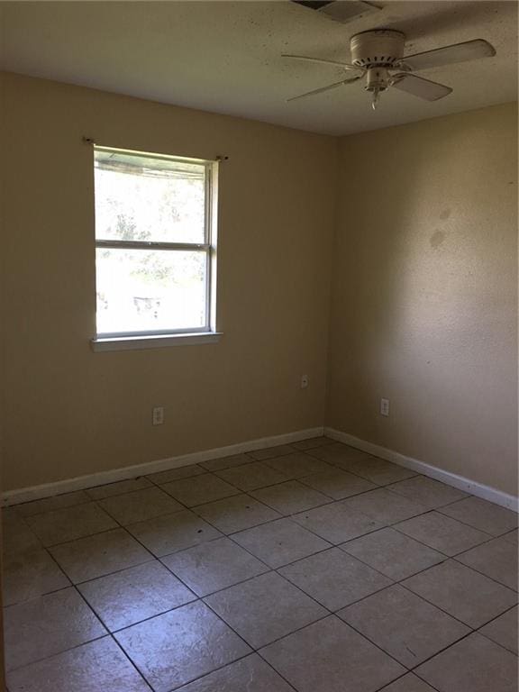 empty room with ceiling fan and light tile patterned floors