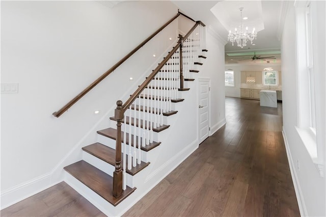 stairs with hardwood / wood-style flooring and ceiling fan with notable chandelier