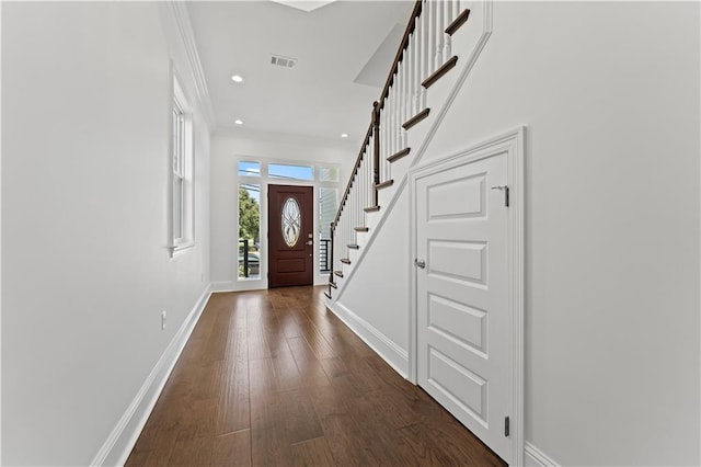 foyer entrance with ornamental molding and dark wood-type flooring