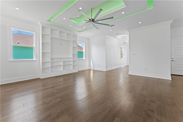 unfurnished living room featuring ceiling fan with notable chandelier, ornamental molding, a tray ceiling, and dark wood-type flooring