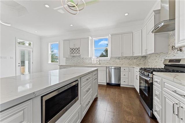 kitchen with white cabinetry, appliances with stainless steel finishes, light stone counters, and wall chimney range hood