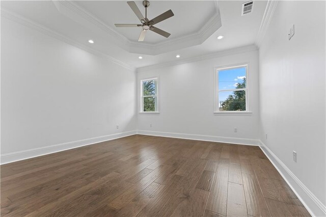 empty room with ornamental molding, a tray ceiling, ceiling fan, and dark hardwood / wood-style flooring