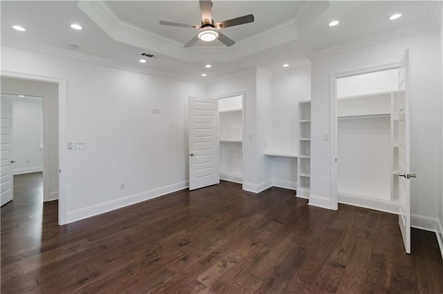 unfurnished bedroom featuring ceiling fan, crown molding, dark hardwood / wood-style flooring, and a walk in closet