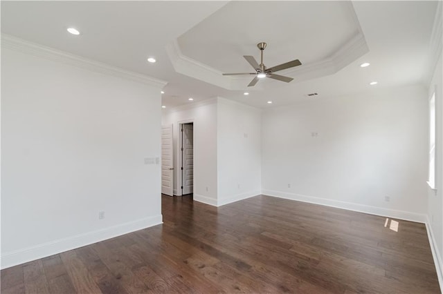 empty room featuring a tray ceiling, ornamental molding, dark wood-type flooring, and ceiling fan