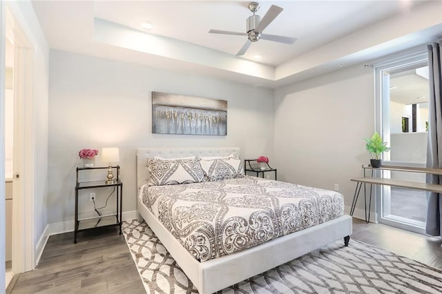 bedroom featuring wood-type flooring, ceiling fan, and a raised ceiling