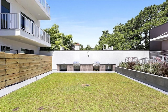 view of yard featuring a balcony and exterior kitchen