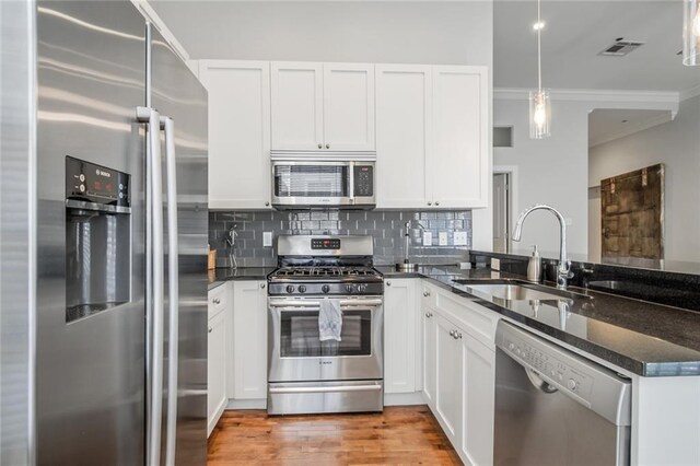 kitchen with stainless steel appliances, white cabinets, hanging light fixtures, and sink