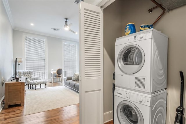 laundry room featuring wood-type flooring, stacked washer and dryer, ceiling fan, and ornamental molding