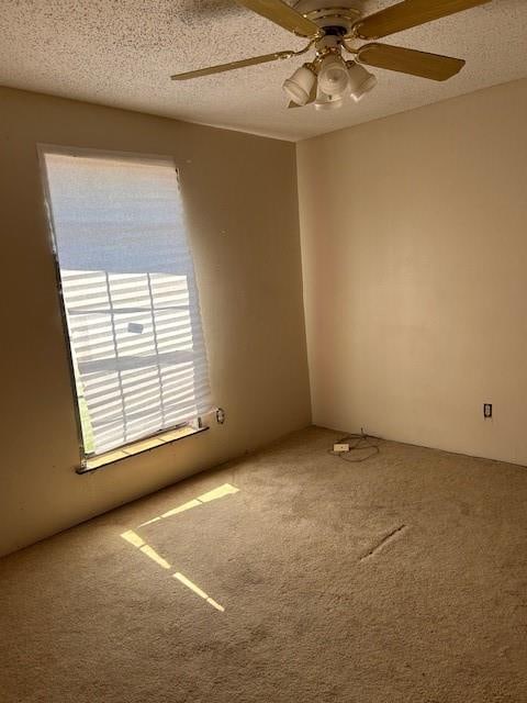 unfurnished room featuring a textured ceiling, carpet flooring, and ceiling fan