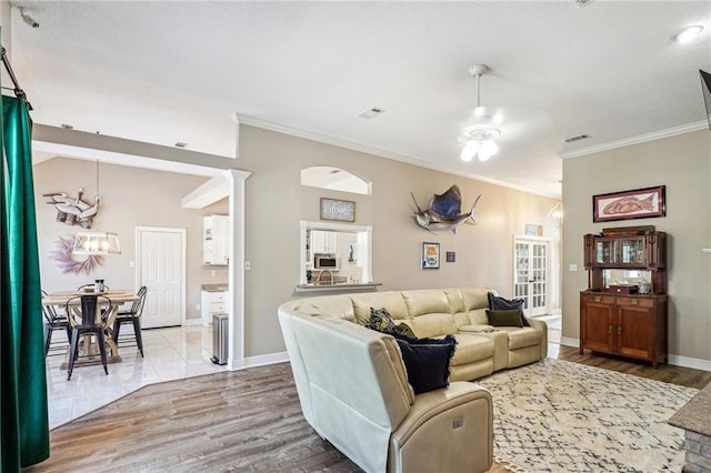 living room with light hardwood / wood-style floors, ornamental molding, and ceiling fan