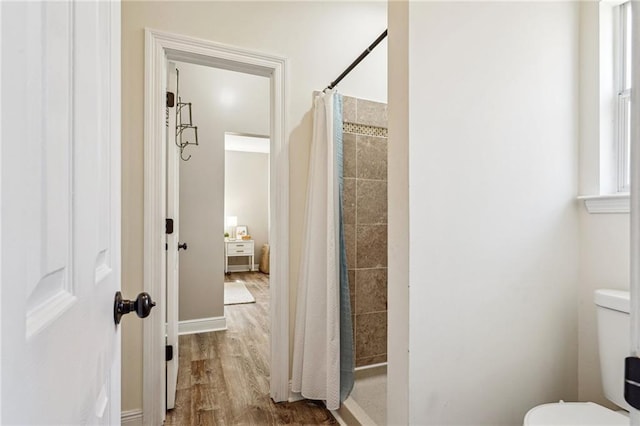 bathroom with wood-type flooring, a shower with curtain, and toilet