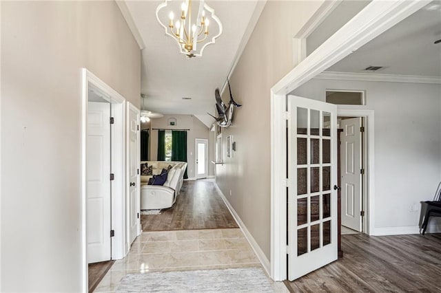 hall featuring an inviting chandelier, light wood-type flooring, and ornamental molding