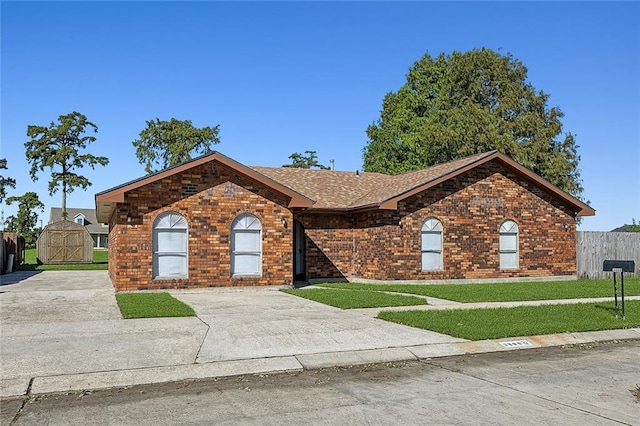 ranch-style home featuring a storage unit and a front lawn