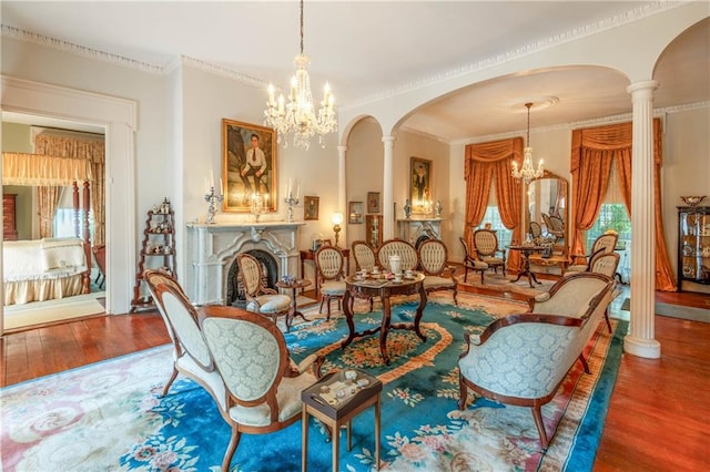 interior space featuring wood-type flooring, an inviting chandelier, crown molding, and ornate columns