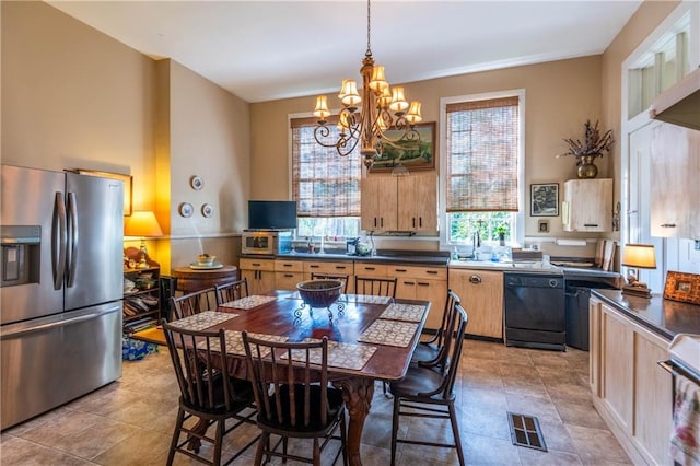 kitchen with appliances with stainless steel finishes, hanging light fixtures, light brown cabinets, sink, and a notable chandelier