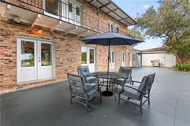 view of patio featuring french doors, outdoor dining area, grilling area, a balcony, and an outdoor structure