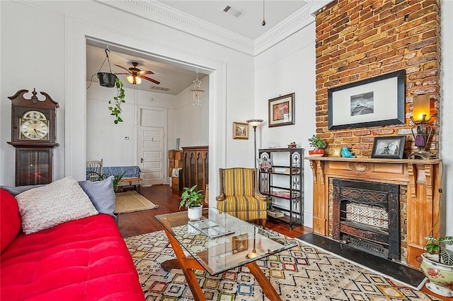 living room featuring ceiling fan, crown molding, a fireplace, and dark hardwood / wood-style flooring