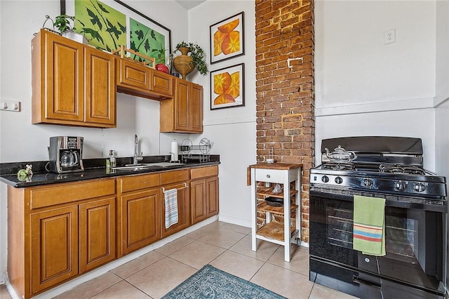 kitchen with light tile patterned flooring, black range with gas cooktop, and sink