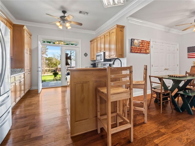 kitchen featuring dark hardwood / wood-style floors, stainless steel appliances, crown molding, ceiling fan, and light brown cabinetry