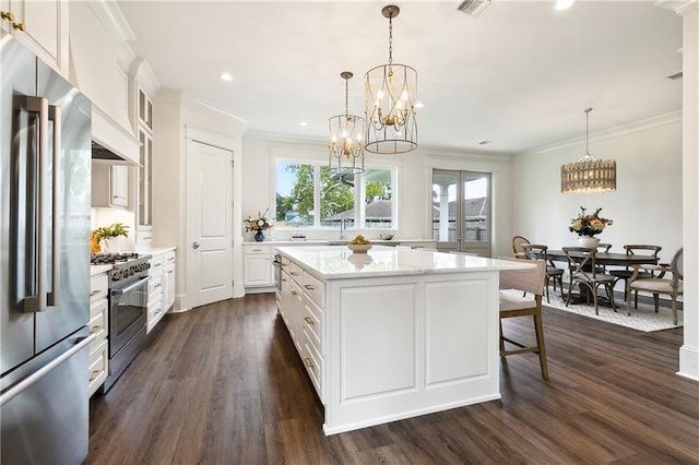 kitchen featuring pendant lighting, a kitchen island, dark hardwood / wood-style flooring, white cabinetry, and stainless steel appliances