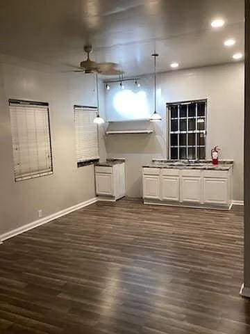 unfurnished living room featuring dark hardwood / wood-style floors, ceiling fan, and track lighting