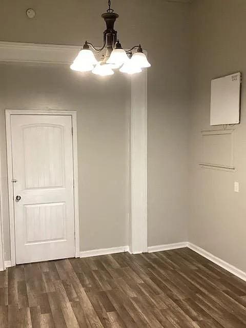 unfurnished dining area with dark hardwood / wood-style flooring and an inviting chandelier